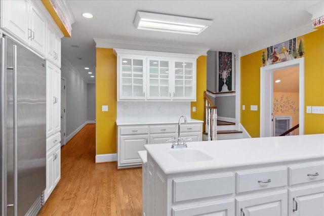 kitchen featuring white cabinetry, sink, ornamental molding, stainless steel built in fridge, and light hardwood / wood-style floors