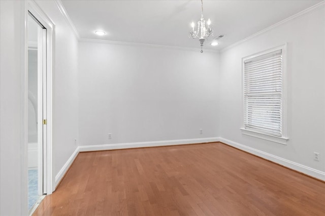 spare room featuring wood-type flooring, ornamental molding, and a notable chandelier