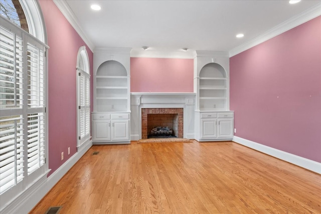 unfurnished living room featuring crown molding, light hardwood / wood-style flooring, built in features, and a healthy amount of sunlight