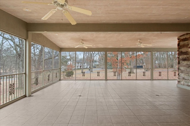 unfurnished sunroom with ceiling fan, a healthy amount of sunlight, and beam ceiling