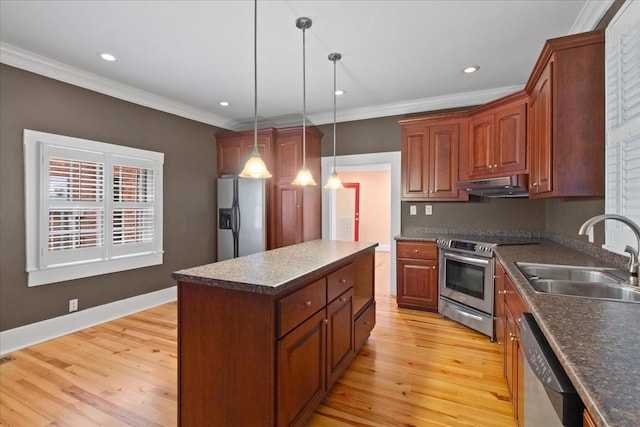 kitchen with a kitchen island, appliances with stainless steel finishes, pendant lighting, sink, and light wood-type flooring