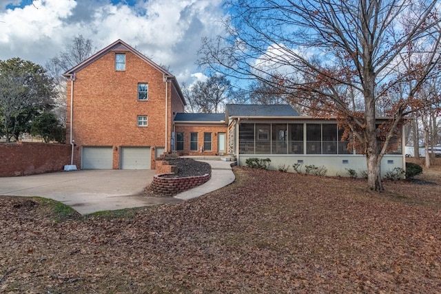 rear view of property with a garage and a sunroom