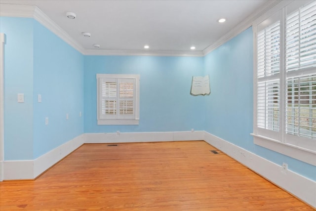 empty room featuring crown molding, plenty of natural light, and light hardwood / wood-style floors