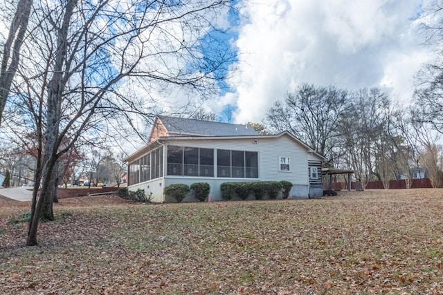 view of side of home featuring a sunroom and a lawn