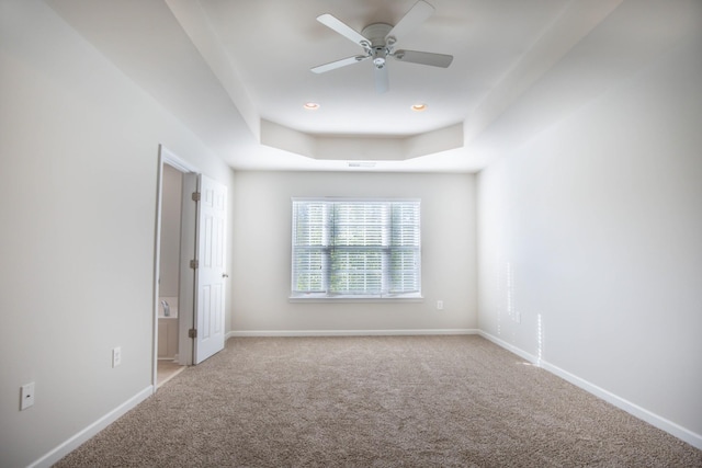 carpeted spare room featuring a raised ceiling and ceiling fan