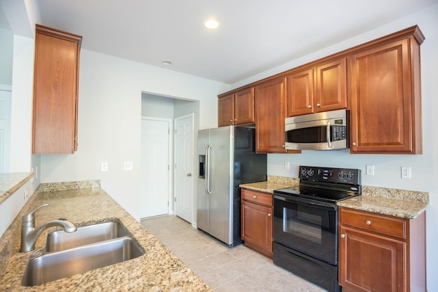 kitchen featuring light stone countertops, sink, light tile patterned floors, and appliances with stainless steel finishes