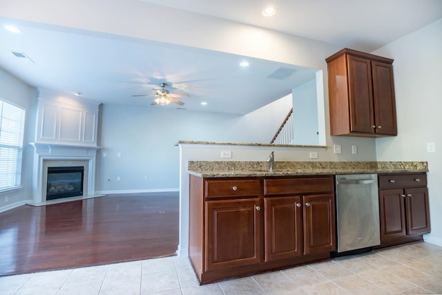 kitchen with sink, stainless steel dishwasher, ceiling fan, light tile patterned floors, and light stone counters