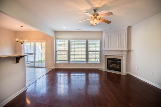 unfurnished living room with dark wood-type flooring and ceiling fan with notable chandelier