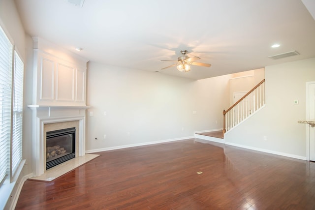 unfurnished living room featuring ceiling fan, a fireplace, and dark wood-type flooring