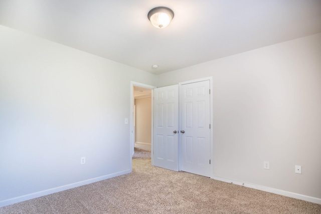 unfurnished bedroom with a closet and light colored carpet