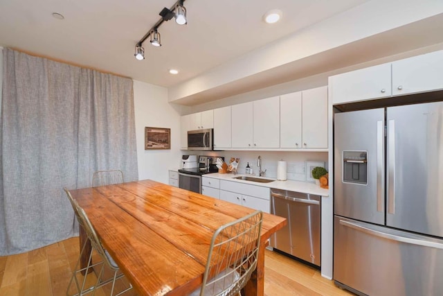 kitchen with white cabinetry, sink, light hardwood / wood-style floors, and appliances with stainless steel finishes