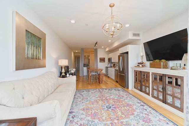 living room with an inviting chandelier and light hardwood / wood-style flooring