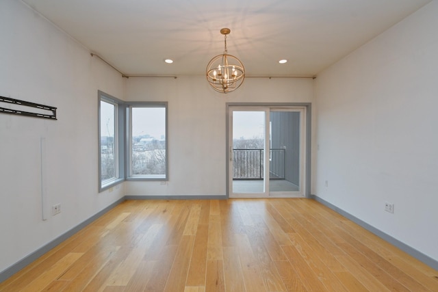 empty room featuring a chandelier and light wood-type flooring