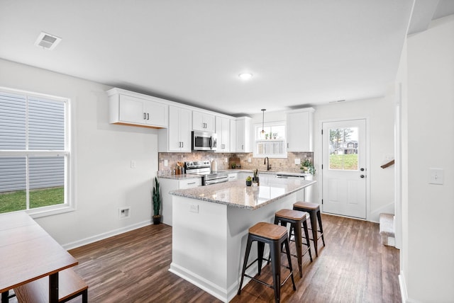 kitchen with tasteful backsplash, dark wood finished floors, appliances with stainless steel finishes, white cabinets, and a sink