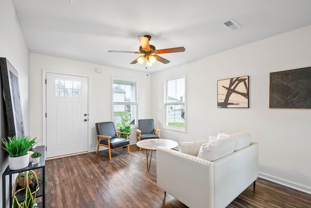 living area featuring visible vents, baseboards, a ceiling fan, and dark wood-style flooring