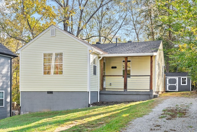 view of front facade with covered porch, a front lawn, and a storage shed