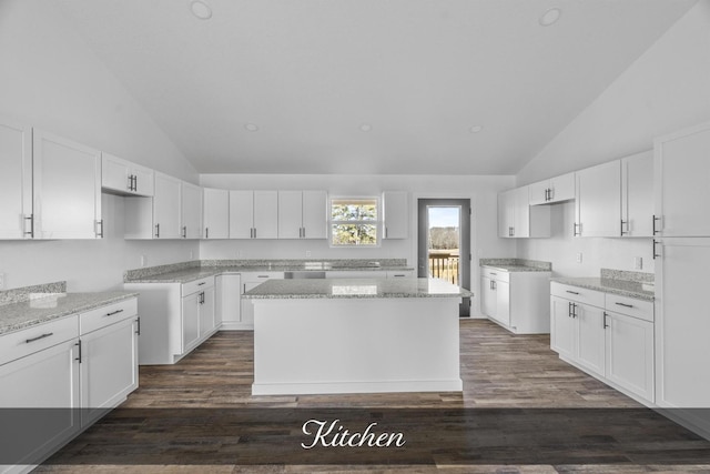 kitchen featuring dark wood-style floors, white cabinetry, light stone counters, and vaulted ceiling