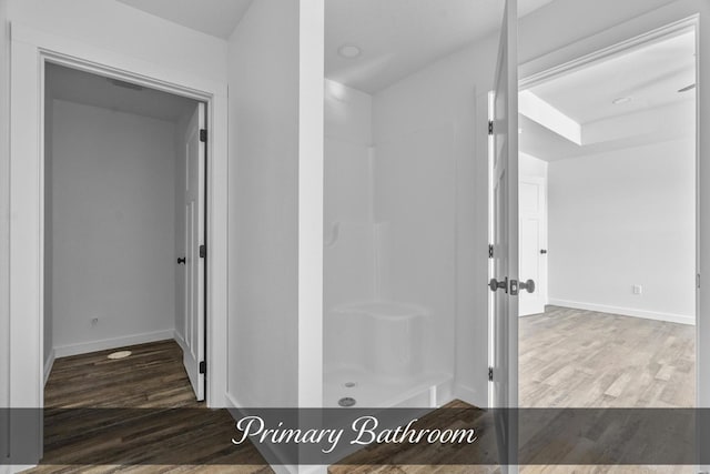 bathroom with a walk in shower, wood finished floors, and baseboards