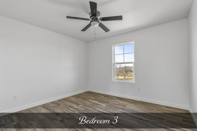 spare room with wood finished floors, a ceiling fan, and baseboards