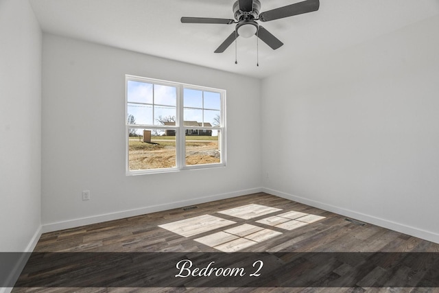 spare room with wood finished floors, a ceiling fan, and baseboards