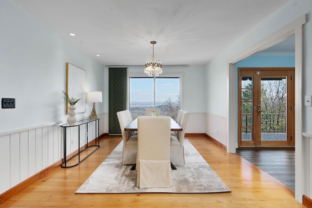 dining room featuring plenty of natural light, light wood-type flooring, crown molding, and a chandelier