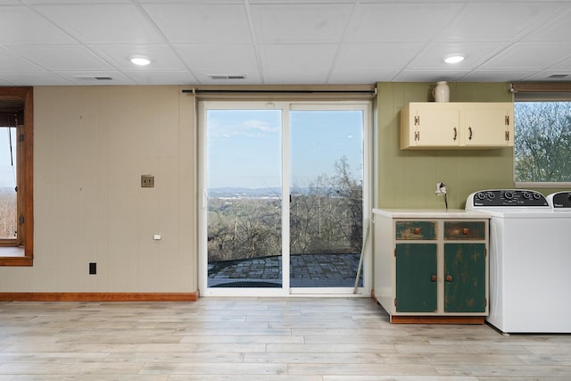 washroom featuring washer and clothes dryer, cabinets, a wealth of natural light, and light hardwood / wood-style flooring