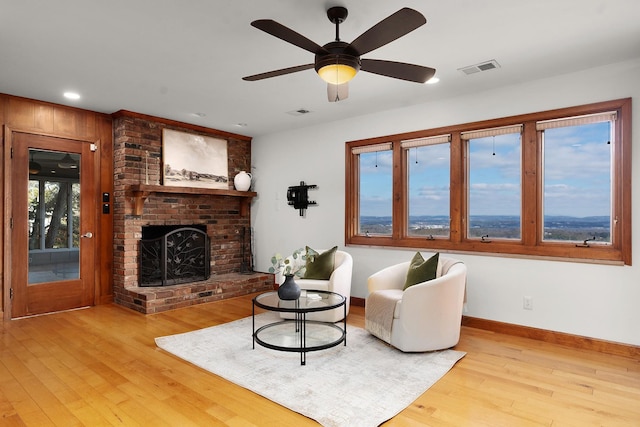 living room with ceiling fan, a fireplace, and light hardwood / wood-style flooring