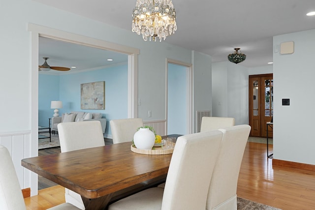 dining space featuring ceiling fan with notable chandelier and wood-type flooring