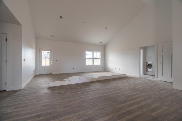 unfurnished living room featuring a healthy amount of sunlight, dark hardwood / wood-style flooring, washer / dryer, and high vaulted ceiling