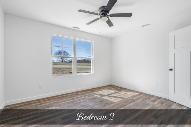 empty room featuring baseboards, visible vents, and wood finished floors