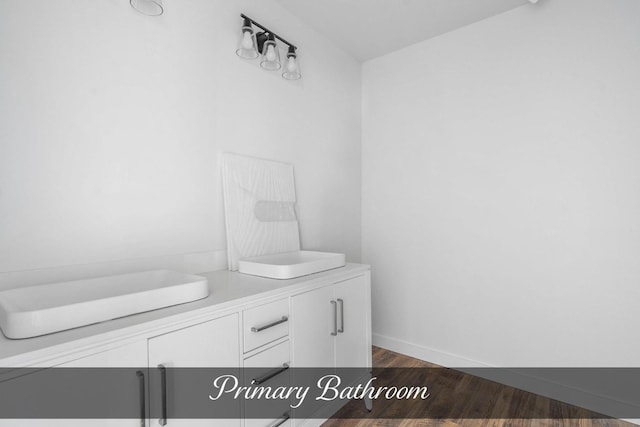 bathroom with double vanity, baseboards, and wood finished floors