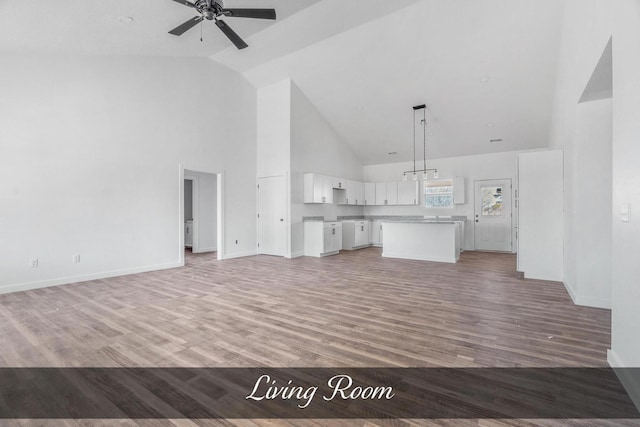 unfurnished living room featuring high vaulted ceiling, ceiling fan, light wood-style flooring, and baseboards