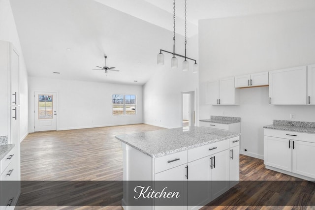 kitchen with high vaulted ceiling, light stone counters, dark wood-style flooring, a ceiling fan, and white cabinets