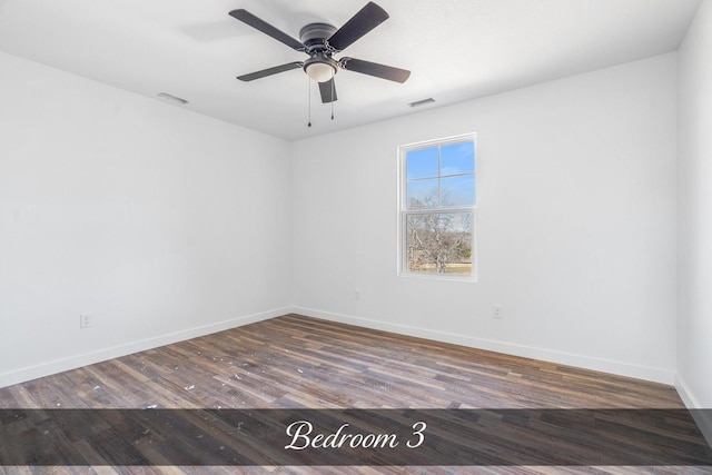 spare room with a ceiling fan, baseboards, visible vents, and wood finished floors