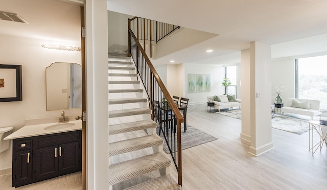 stairs featuring wood-type flooring and sink