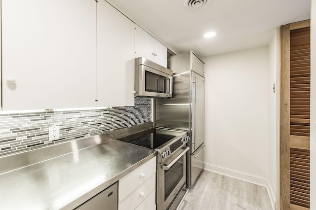 kitchen featuring stainless steel counters, stove, white cabinets, and light wood-type flooring