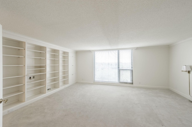 carpeted spare room featuring built in shelves, a textured ceiling, and crown molding