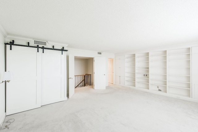 basement with a barn door, light carpet, and a textured ceiling