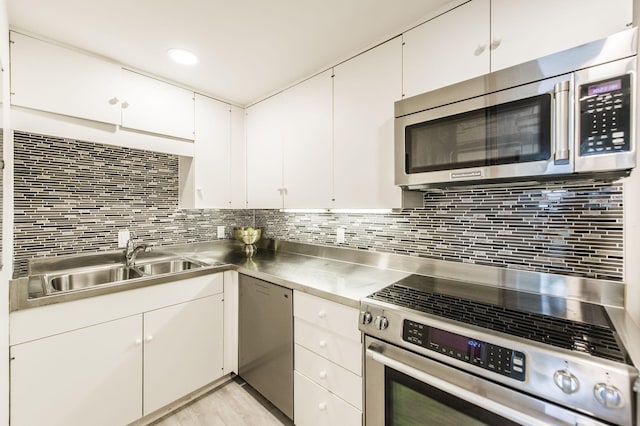 kitchen featuring white cabinetry, sink, stainless steel counters, backsplash, and appliances with stainless steel finishes