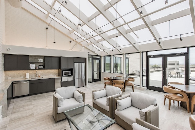 living room featuring french doors, a towering ceiling, and sink