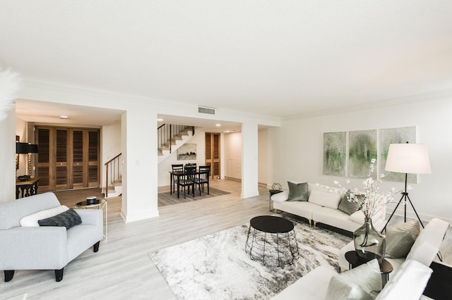 living room with crown molding and light hardwood / wood-style flooring