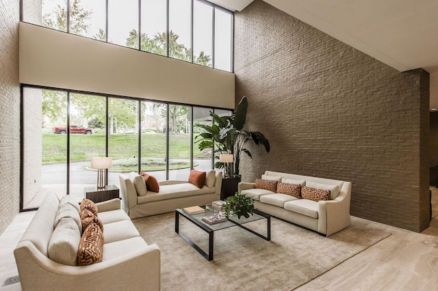 living room featuring a wealth of natural light, brick wall, and a high ceiling