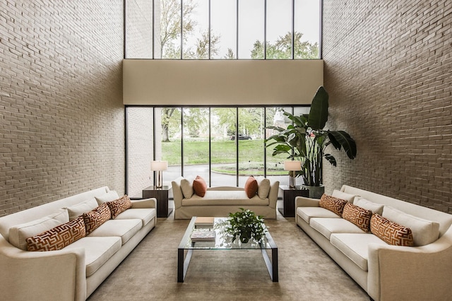 living room featuring a towering ceiling and brick wall