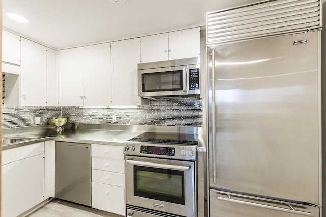 kitchen featuring decorative backsplash, stainless steel counters, white cabinetry, and high quality appliances