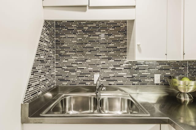 details featuring backsplash, white cabinetry, and sink