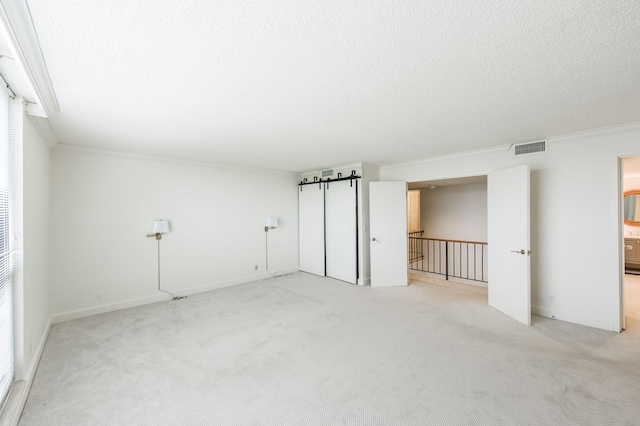 carpeted spare room with a textured ceiling and ornamental molding