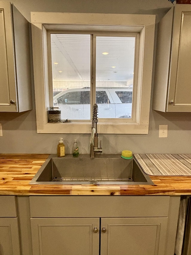 details with gray cabinets, sink, and butcher block counters