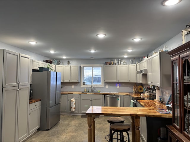 kitchen with stainless steel appliances, gray cabinets, sink, and wooden counters