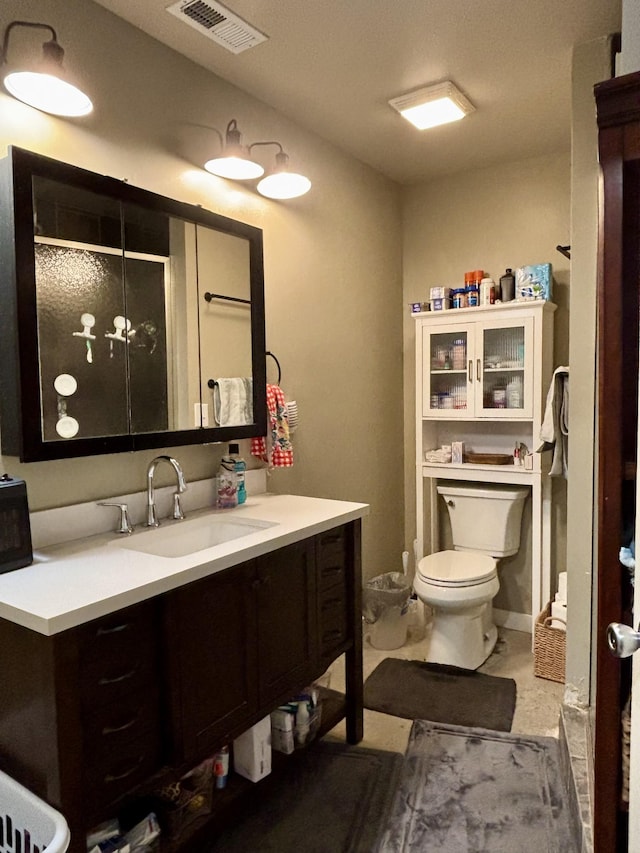 bathroom featuring vanity, toilet, and a shower with shower door