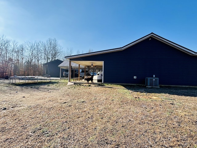 rear view of property featuring ceiling fan, cooling unit, and a trampoline